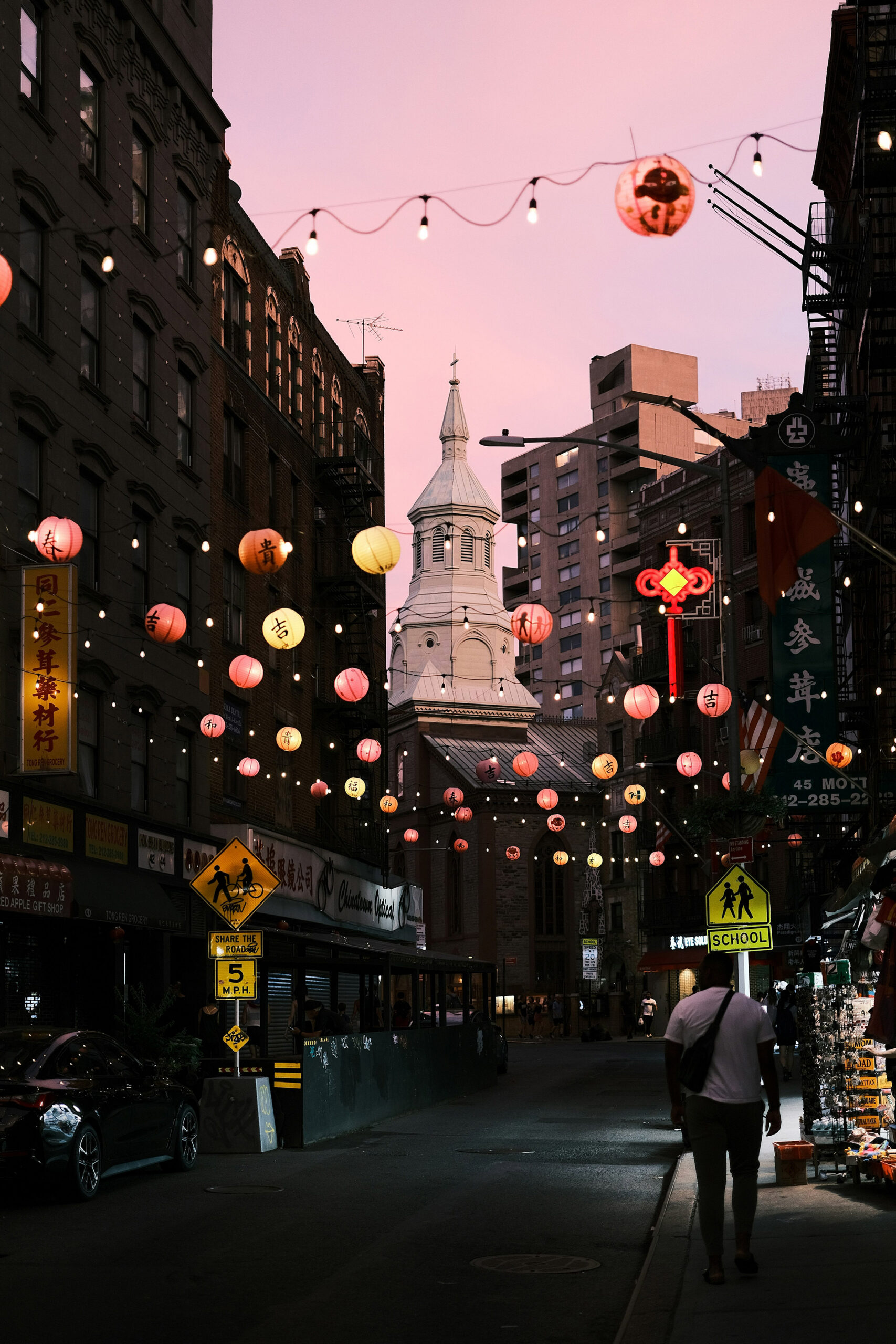 Chinatown street at dusk with red and yellow lanterns strung overhead